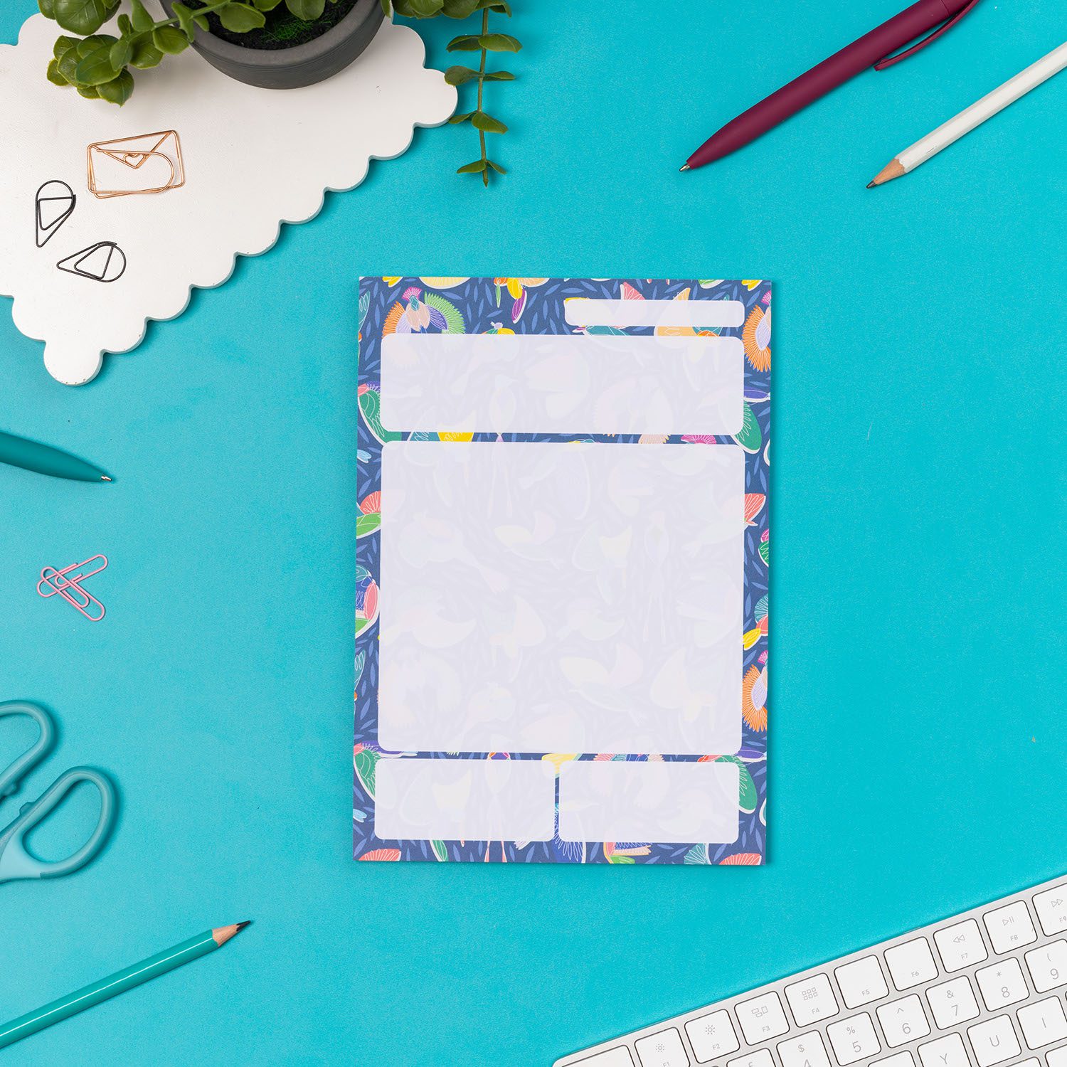 Paradise A5 Daily Planner Pad is central on a teal desk, with pens and a small plant around it.