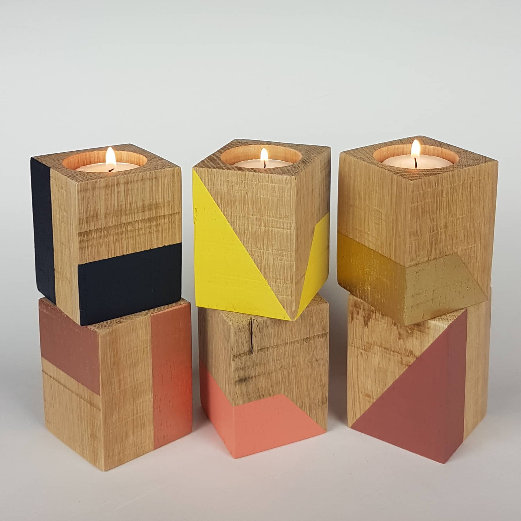 Group of tall wooden tealight holders with coloured geometric shapes