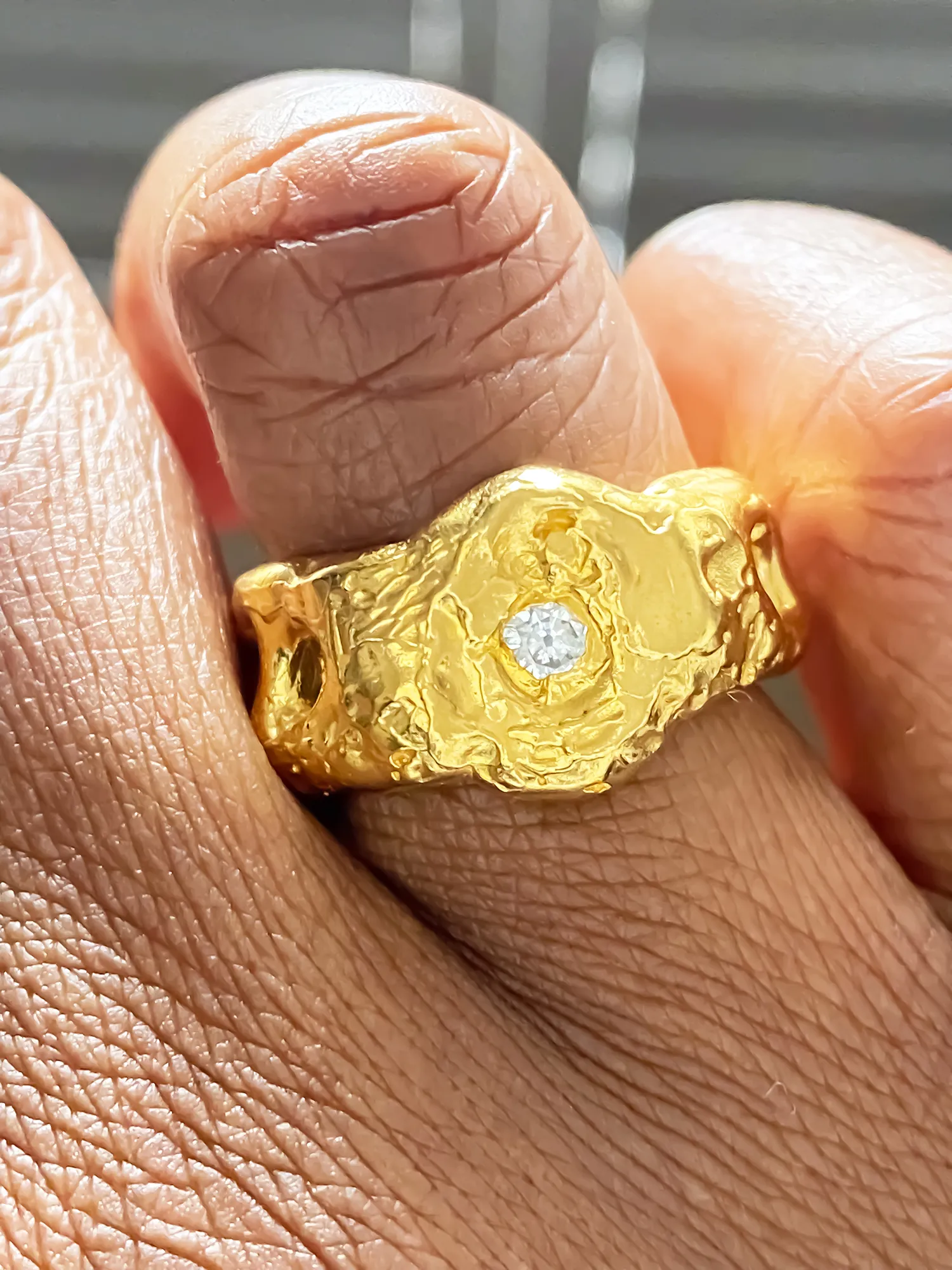 Handcrafted gold ring with textured cutouts and gemstone