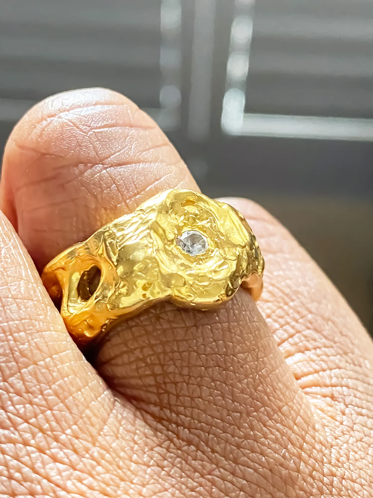 Gold cutout ring with white gemstone worn on hand