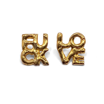 Gold ‘FUCK’ and ‘LOVE’ earrings laid flat on white background
