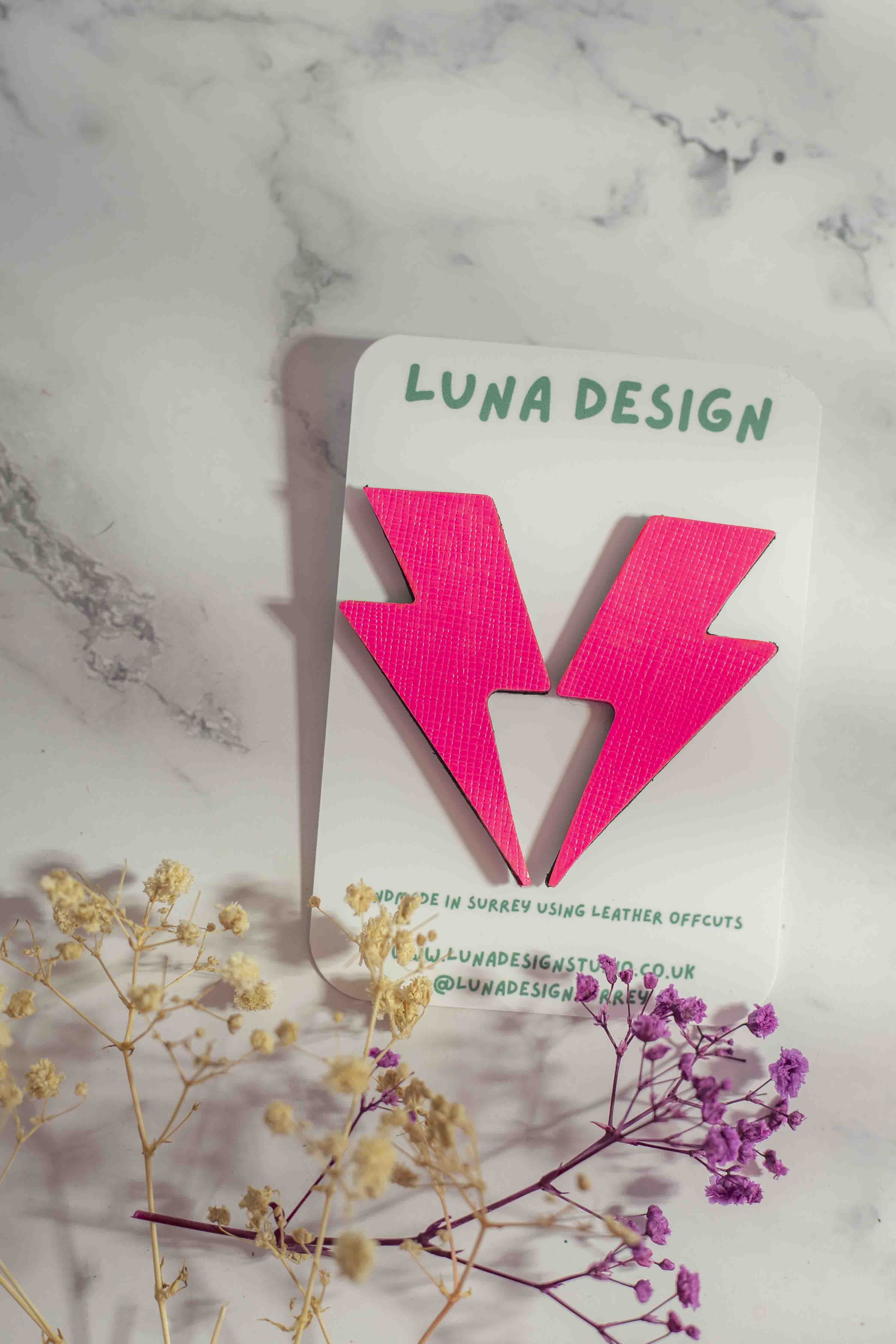 Extra-large neon pink lightning bolt stud earrings close up